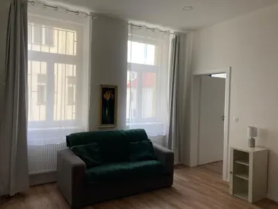 a living room with a green couch and two windows at Enter City Center in Prague