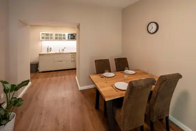 a dining room table with chairs and a clock on the wall at Downtown - Apart Hotel Zborovska in Prague