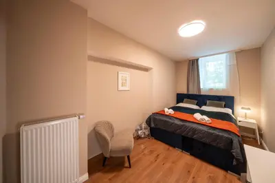 a bedroom with a bed and a chair and a window at Downtown - Apart Hotel Zborovska in Prague