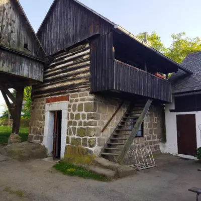 an old stone building with a wooden balcony on it at Apartmán Roubenka na Dobřeni in Mělník