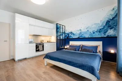 a bedroom with a blue bed and a kitchen at AuriApartments Libeň nový byt 1kk s garáží in Prague