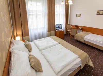 a hotel room with two beds and a desk at Novoměstský hotel in Prague