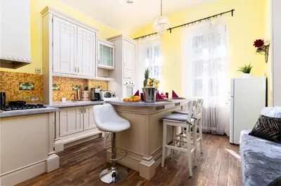 a kitchen with yellow walls and white cabinets and a counter at Magnificent King Suite in Prague