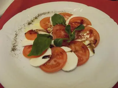 a plate of food with tomatoes and greens on it at Hotel Trumf in Mladá Boleslav