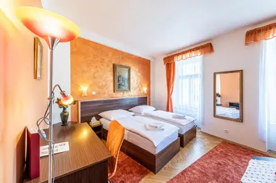 a hotel room with two beds and a desk at Hotel Trumf in Mladá Boleslav
