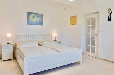 a white bedroom with a white bed and two lamps at Apartmán u Berounky in Beroun