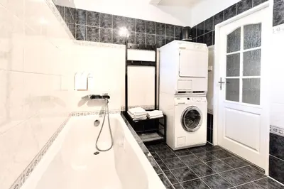 a bathroom with a tub and a washer and dryer at Apartmán u Berounky in Beroun