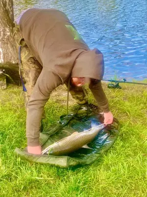 a person bending over a fish on the grass at Apartmán u Berounky in Beroun
