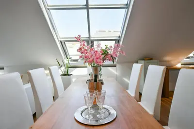 a vase of flowers on a wooden table with white chairs at LUXURY CENTRAL PENTHOUSE WITH SAUNA, TERRACE, 250m2, 5BDRM, 3BTHRM in Prague