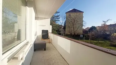 a balcony with a window with a chair and a clock tower at Apartment Dream in Prague