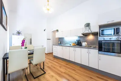 a kitchen with white cabinets and a table with chairs at Wenceslas Square 2 Bedroom Apartment in Prague