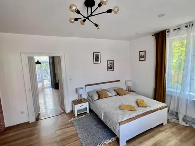 a white bedroom with a bed and a chandelier at Apartments Old Town in Brandýs nad Labem-Stará Boleslav