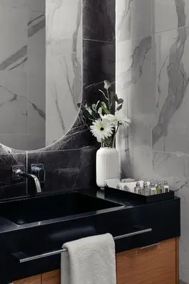 a bathroom with a black sink and a vase of flowers at U Pujcovny Apartment Old Town Prague in Prague