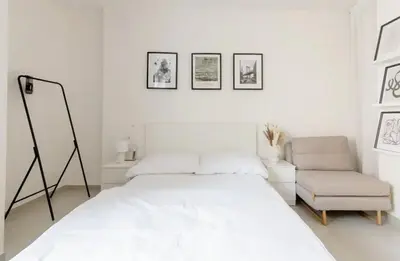 a white bedroom with a bed and a chair at Cozy & New Studio Apartment PEACE SQ. in Prague