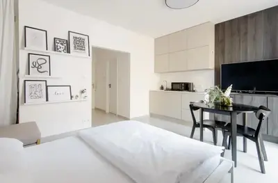 a white living room with a table and a kitchen at Cozy & New Studio Apartment PEACE SQ. in Prague