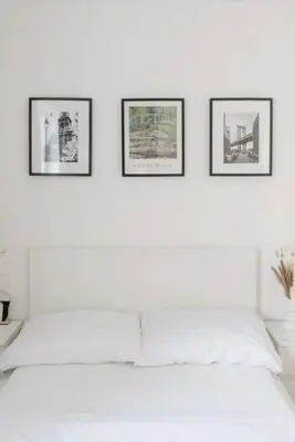 a white bedroom with three pictures on the wall at Cozy & New Studio Apartment PEACE SQ. in Prague