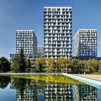 two tall buildings in a city with a reflection in the water at Garden Park Studio in Prague