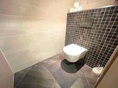 a bathroom with a toilet and a tiled wall at Garden Park Studio in Prague