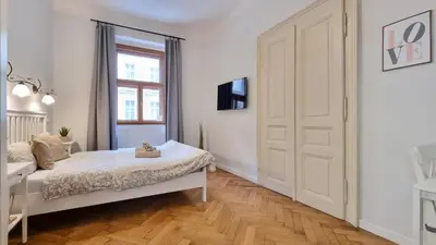 a white bedroom with a bed and a window at Finnem Rentals Florenc in Prague