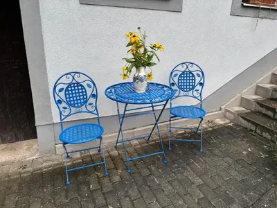 a table with three chairs and a vase with flowers on it at Apartmán U jezírka in Velké Přílepy