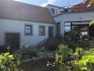 a house with a pond in front of it at Apartmán U jezírka in Velké Přílepy