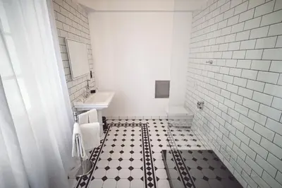 a bathroom with a black and white tiled floor at Domus Balthasar Boutique Hotel in Prague