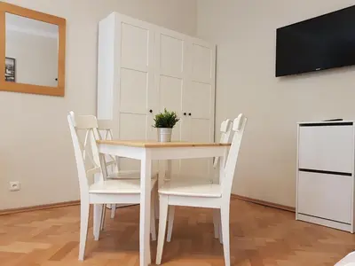 a white dining room table with white chairs and a tv at Finnem Rentals Pod Znonařkou in Prague