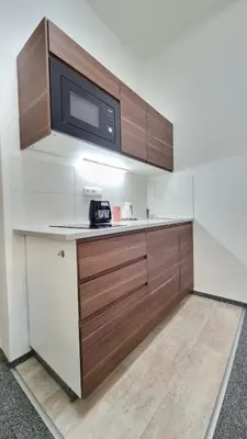 a kitchen with wooden cabinets and a microwave at Finnem Rentals Pod Znonařkou in Prague