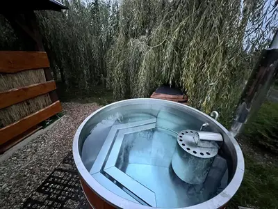 a bath tub filled with water next to a field at Domek u rybníka in Schloss Bösig