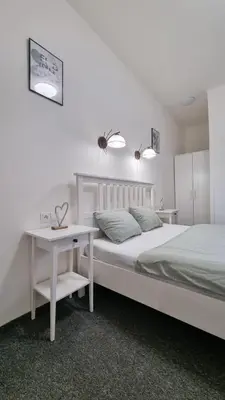 a white bedroom with a bed and a desk at Finnem Rentals Jičínská in Prague