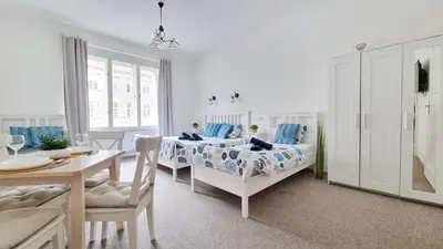 a white room with two beds and a dining table at Finnem Rentals Zíkova in Prague