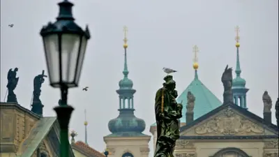 a statue in front of a building with a street light at Apartment Sedlčanská - You Will Save Money Here - equipped with antique furniture in Prague