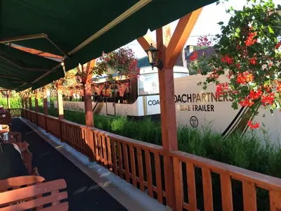 a restaurant with a deck with flowers and a food truck at Hotel ELMA in Srbsko