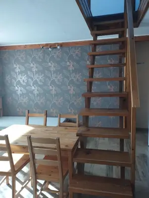a dining room with a wooden table and a spiral staircase at Apartmány Audy in Mníšek pod Brdy