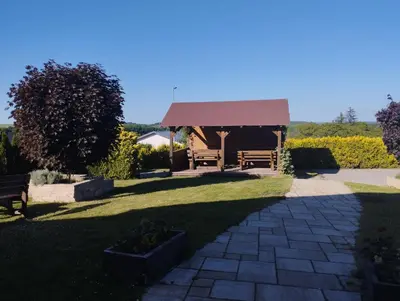 a gazebo with two benches in a yard at Apartmány Audy in Mníšek pod Brdy