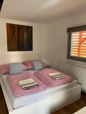 a bed with pink sheets and pillows in a bedroom at Apartmán - F - Vyhlídka nad řekou in Zdiby