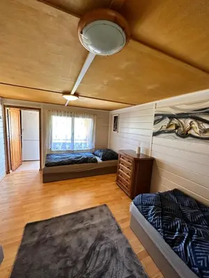 a room with two beds and a table and a ceiling at Chata U Řeky in Volenice