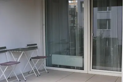 a balcony with a glass door with two chairs and a table at Holešovice Delight: Modern Comfort with a Twist in Prague 7 in Prague