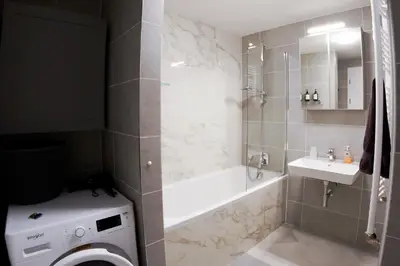a bathroom with a bath tub and a sink at Holešovice Delight: Modern Comfort with a Twist in Prague 7 in Prague