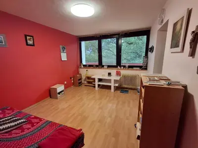 a living room with red walls and a wooden floor at Pokoj v rodinném se sdílenou koupelnou in Černošice