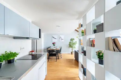 a kitchen with white cabinets and a dining room with a table at Duplex apartment with AC in Prague Center in Prague
