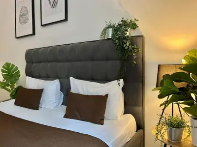 a bed with white pillows and plants on it at Beautiful New Town Apartment in Prague