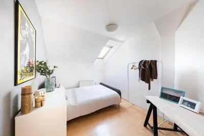 a small white bedroom with a bed and a desk at Bohéme Apartment Prague Three in Prague
