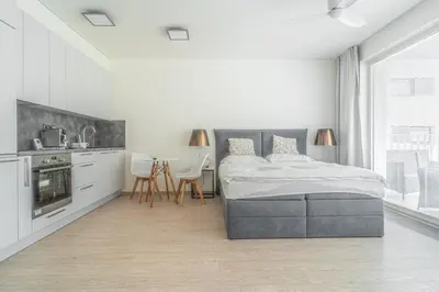 a white bedroom with a bed and a table at Apartment Karel with garage parking in Prague