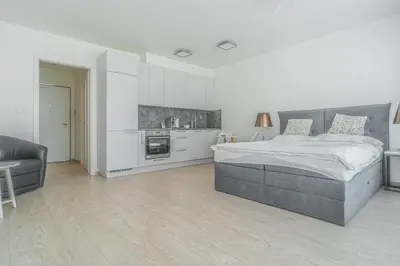 a white bedroom with a large bed and a kitchen at Apartment Karel with garage parking in Prague