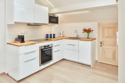 a white kitchen with white cabinets and a wooden floor at Karlova Old Town Apartments in Prague