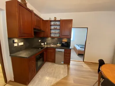 a kitchen with wooden cabinets and a sink and a table at Penzion Mořina in Mořina