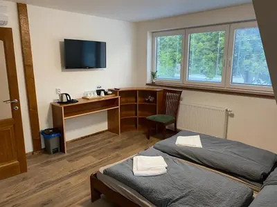 a bedroom with two beds and a desk with a computer at Penzion Mořina in Mořina