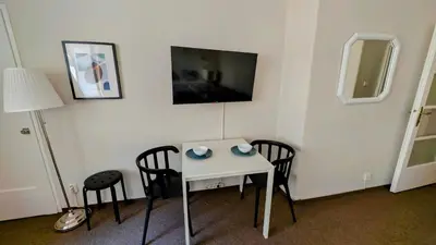 a white table with two chairs and a television on a wall at Flat in Zizkov -104- in Prague