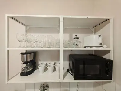 a cabinet with a microwave and some cups and glasses at Apartment in Zizkov -201- in Prague